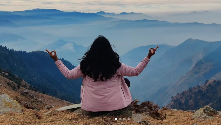 Megha seated in meditation, looking out across the mountains