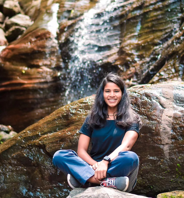 Dr Megha Pundir seated beside a waterfall