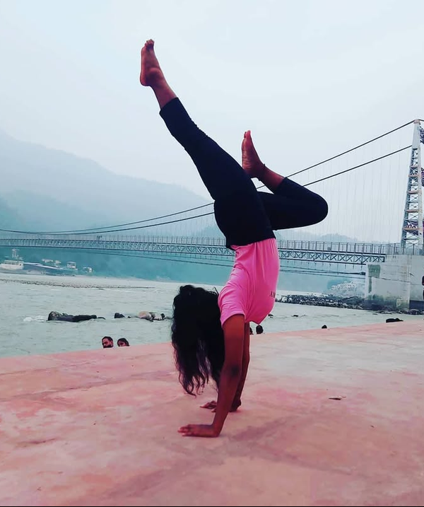 Megha practising a handstand beside a river